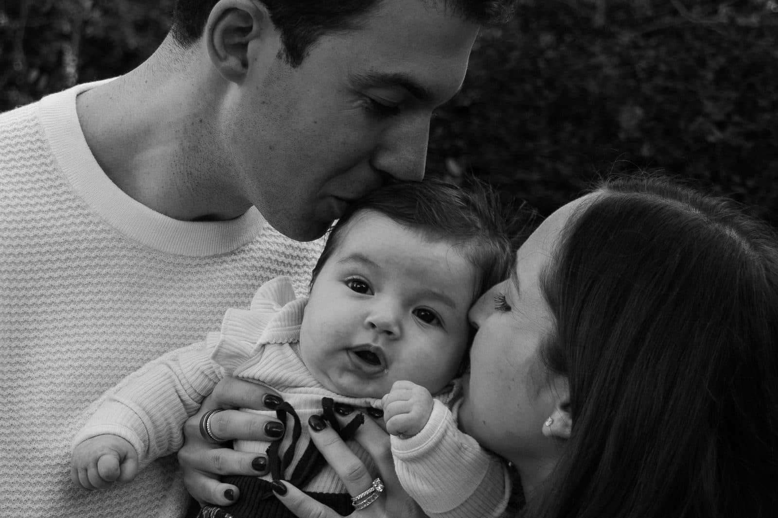 Parents kissing baby